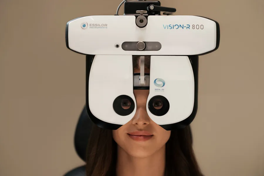 Patient looking into a phoropter during a comprehensive eye exam